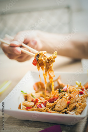 man hand with chopsticks eat thai food closeup selective focus