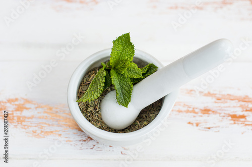 Fresh mint leaves in a mortar on a white wooden table. Dried herb. photo
