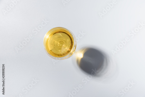 Wineglass of white wine with shadows on gray background. Top view. Holiday celebration concept