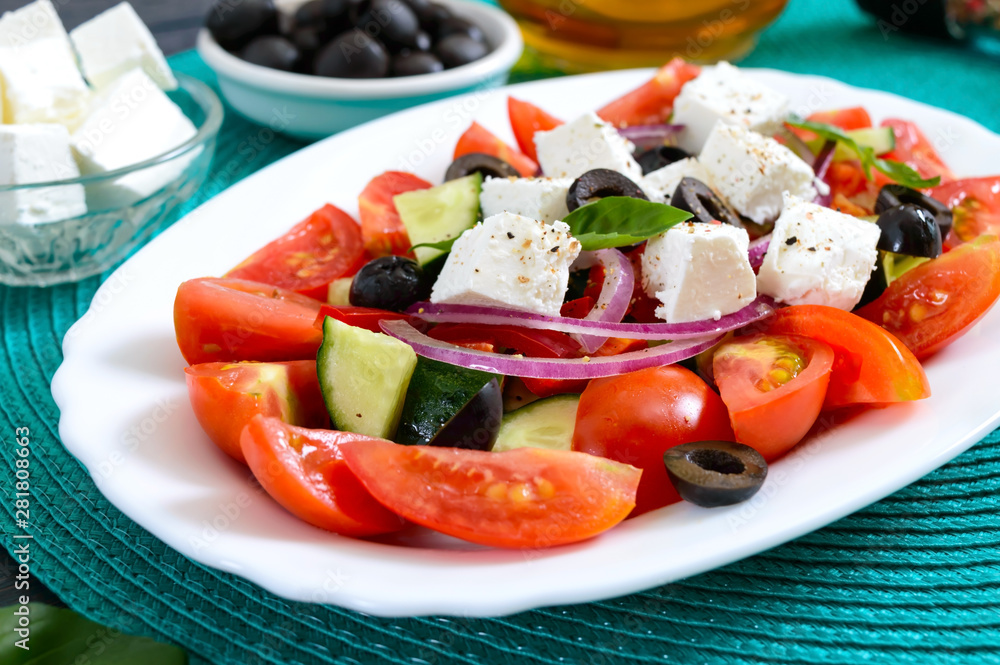 Tasty vitamin salad with fresh vegetables, feta, black olives, basil sauce on a white plate on a wooden background. Tasty vitamin salad with fresh vegetables, feta, black olives, basil sauce on a white plate on a wooden background.