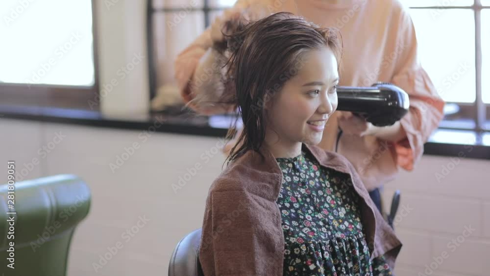 Hairdresser drying hair of female customer with hair dryer Stock ビデオ Adobe Stock