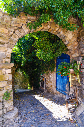 Fototapeta Naklejka Na Ścianę i Meble -  A narrow alley in the medieval village of Bussana Vecchia, former ghost town in Ligurian Riviera with stone buildings ruined from an earthquake in 1887 and now repopulated by artists, Imperia, Italy