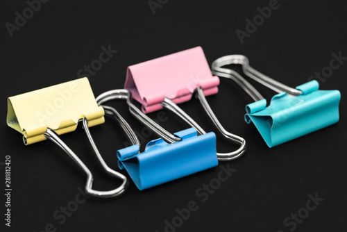 Colored binder clip on black background