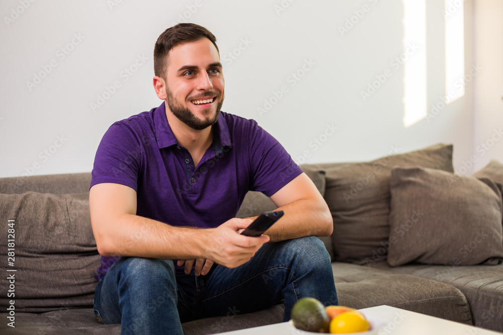 Man watching tv while sitting on sofa in his living room. Man watching tv while sitting on sofa in his living room.