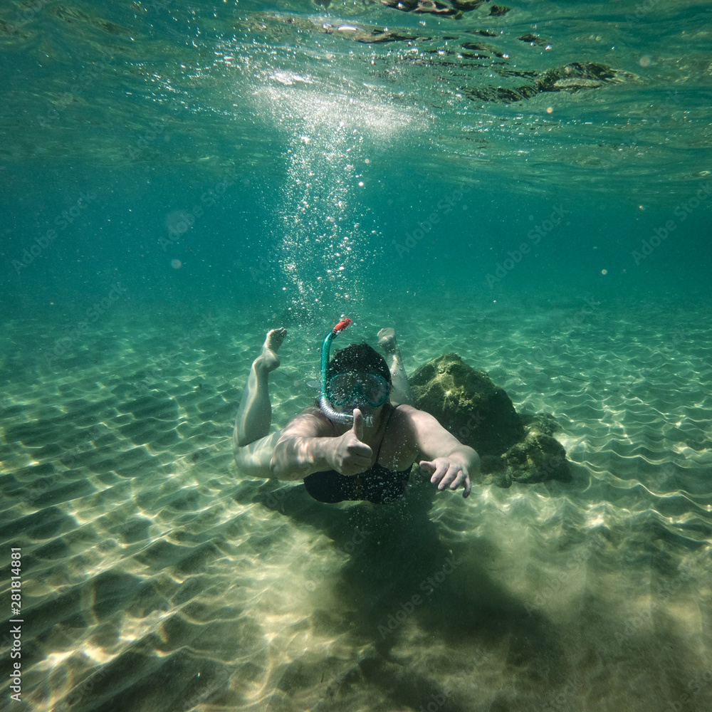 Underwater background with a diving woman in the ocean water. At the bottom of the sea.