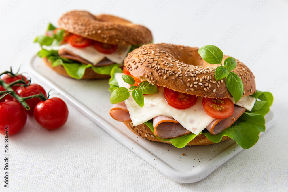 Delicious Bagels sandwiches with cheese, ham, cherry tomatoes and salad for breakfast. Copy space Delicious Bagels sandwiches with cheese, ham, cherry tomatoes and salad for breakfast. Copy space