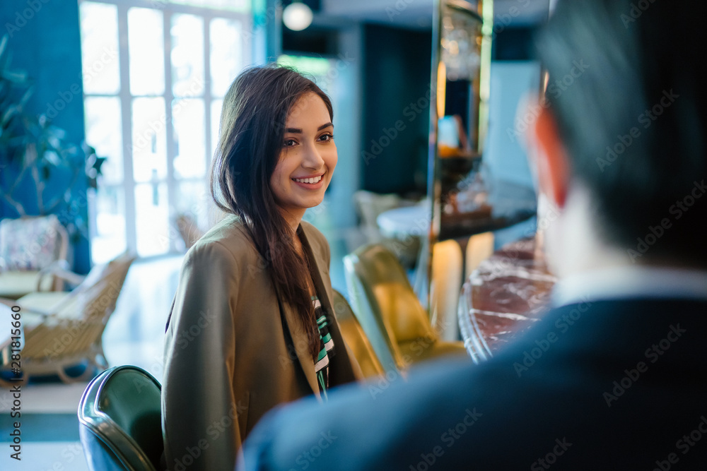 Εκτύπωση καμβά A beautiful, elegant and attractive Indian woman sits beside a young and handsome Chinese Asian man in a suit in a well-decorated interior