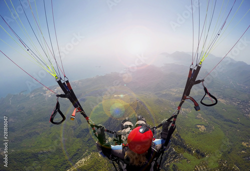 Paragliding in the sky. Woman girl is soaring in the sky on paraplane above mountains ans sea 