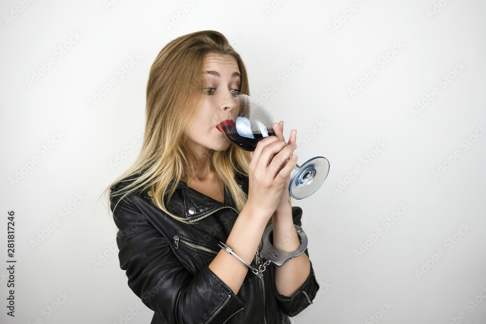 Wall Mural young blonde woman wearing black leather jacket drinks wine and being arrested a