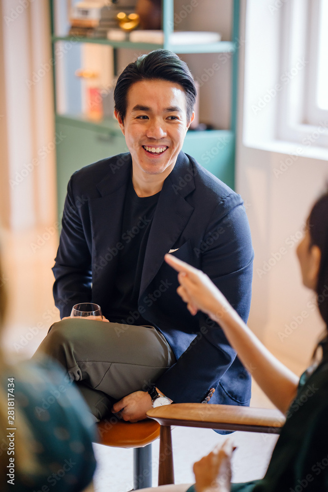 Φωτογραφία A young and attractive Chinese Asian man in a well-fitted navy suit and pocket square is talking to his companion in a meeting
