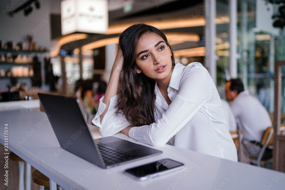 Φωτογραφία A young and attractive Indian Asian woman looks pensive and concerned as she looks up from her laptop computer