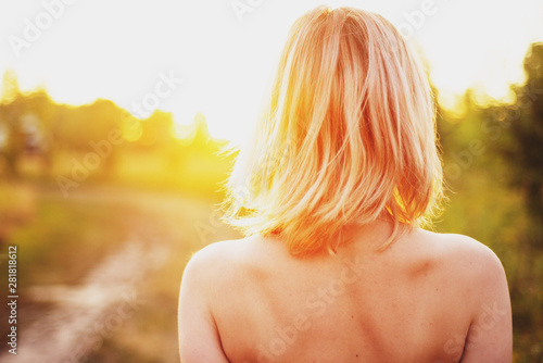  tender girl with a bare back in a summer meadow at sunset