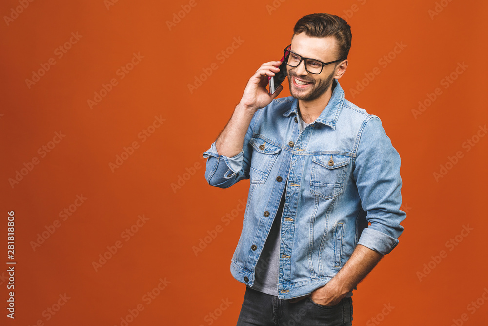 Happy smiling young man talking on mobile isolated on orange background. Happy smiling young man talking on mobile isolated on orange background.