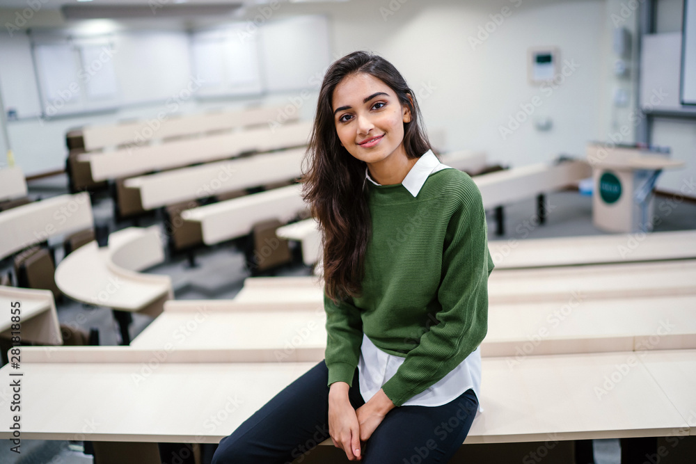 Φωτογραφία Portrait of a beautiful, young and attractive Indian Asian business woman smiling as she sits in a seminar room during the day