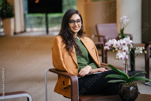Photography Portrait of a young, beautiful, intelligent and attractive Indian Asian woman MBA student smiling as she sits in her campus during the day