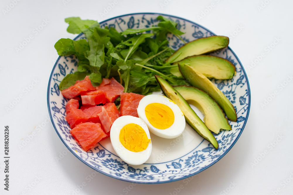 eggs, avocado and red fish fillet in a bowl on white background close up eggs, avocado and red fish fillet in a bowl on white background close up