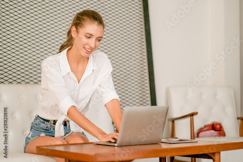 Pretty and beautiful girl sit on sofa and use laptop on table for working and look happy with concept of working at home.