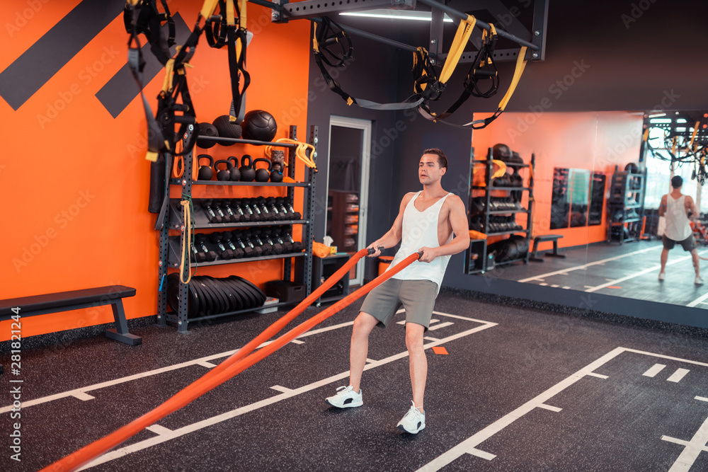 Fototapeta premium Nice sportive young man holding orange ropes