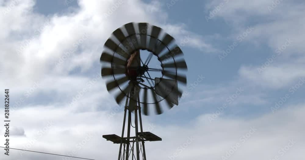 Close up of a wind pumps blades rotating with a background of moving clouds Close up of a wind pumps blades rotating with a background of moving clouds