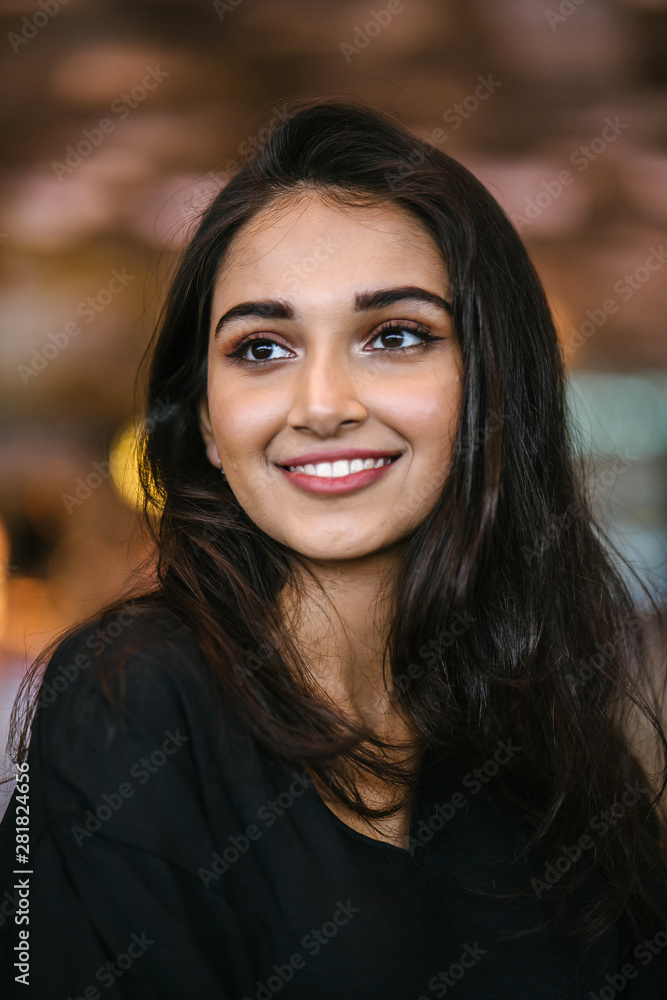 A close up portrait of a beautiful, young, attractive and photogenic Indian Asian girl during the day in the city. She is wearing a casual black dress and smiling radiantly. A close up portrait of a beautiful, young, attractive and photogenic Indian Asian girl during the day in the city. She is wearing a casual black dress and smiling radiantly.