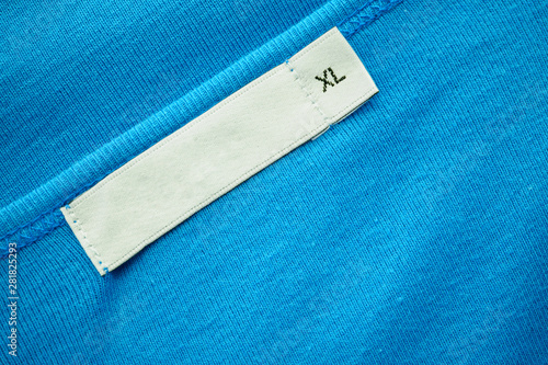 Blank white clothes tag label with XL size on new blue shirt photo