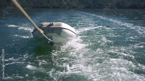SLOWMO - Inflatable boat being towed on rope behind boat on sea of New Zealand