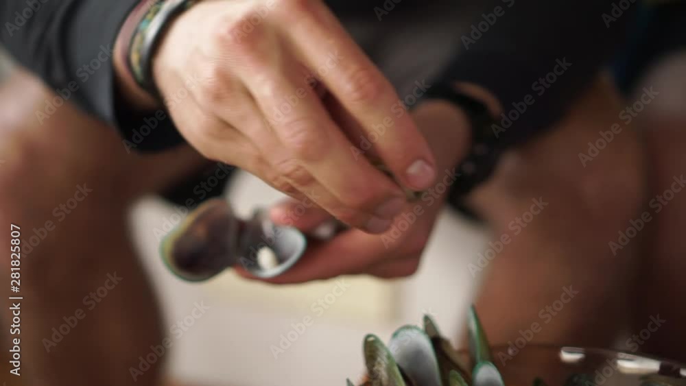 Caucasian man opens freshly caught New Zealand greenshell mussel and dips in sauce - close up Caucasian man opens freshly caught New Zealand greenshell mussel and dips in sauce - close up
