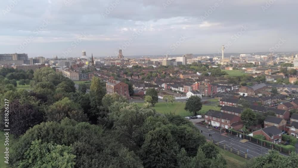 Liverpool city skyline cathedrals & radio city tower on waterfront distant aerial view. Pull back descent over park trees. Liverpool city skyline cathedrals & radio city tower on waterfront distant aerial view. Pull back descent over park trees.