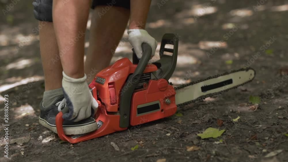 Caucasian hands attempt to start chainsaw on the forest floor, handheld Caucasian hands attempt to start chainsaw on the forest floor, handheld
