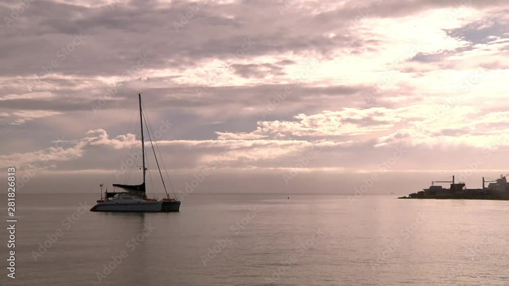 Lonely Sailboat Anchored in Calm Sea Water Near Pier Under Sunset Sunlight Lonely Sailboat Anchored in Calm Sea Water Near Pier Under Sunset Sunlight