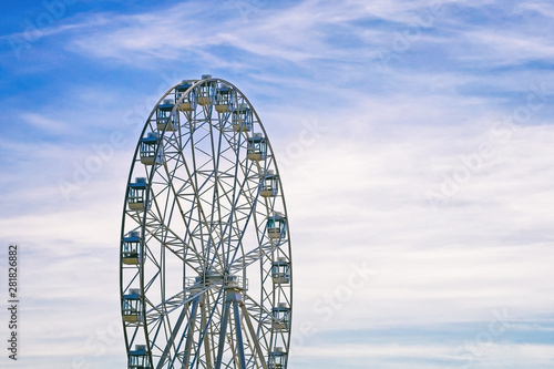 amusement ride ferris wheel on the background a blue sky with snow-white clouds
