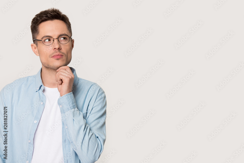 Pensive thoughtful young man pose on grey background looking aside Pensive thoughtful young man pose on grey background looking aside
