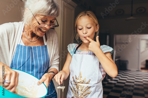 Konstfotografi Grandmother and kid having fun making cake in kitchen