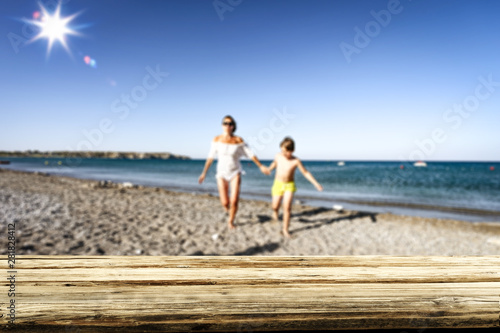 Wooden table top background with family playing and having fun on the beach.