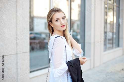 Active lifestyle of a young blonde beautiful student girl in white shirt and black pants walking to work in the office.