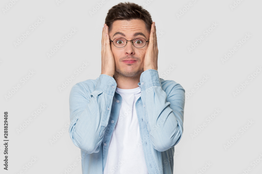 Worried guy holding head in hands pose on grey background Worried guy holding head in hands pose on grey background