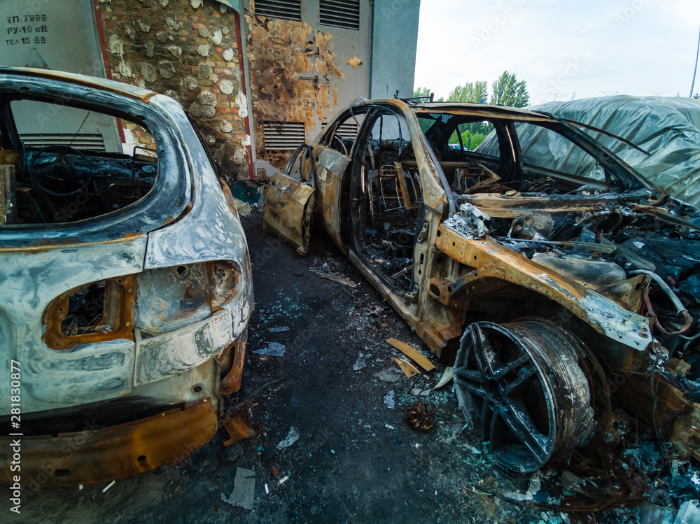 Two cars after the fire. Two burned out cars with an open hood. Arson, burnt car