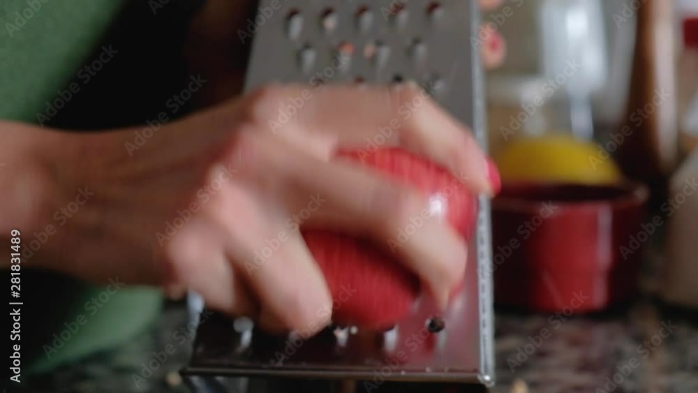 Close up of woman hands grating a red apple with skin on a metallic grater Close up of woman hands grating a red apple with skin on a metallic grater