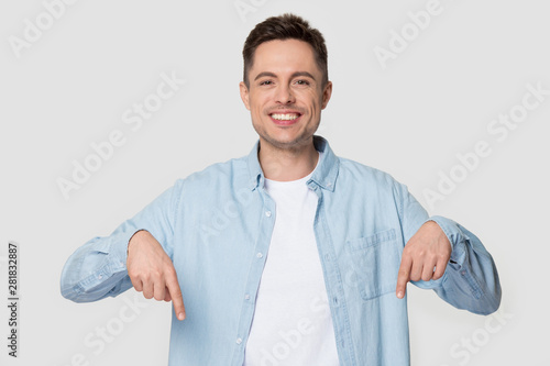 Happy man isolated on grey background pointing fingers down photo