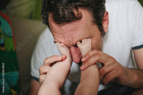 Wallpaper Mural Father of a newborn playing peekaboo with the baby by placing its feet on his eyes Torontodigital.ca
