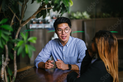 Canvas Print A young Asian business woman during a consultation with a young Korean Asian man for business advice