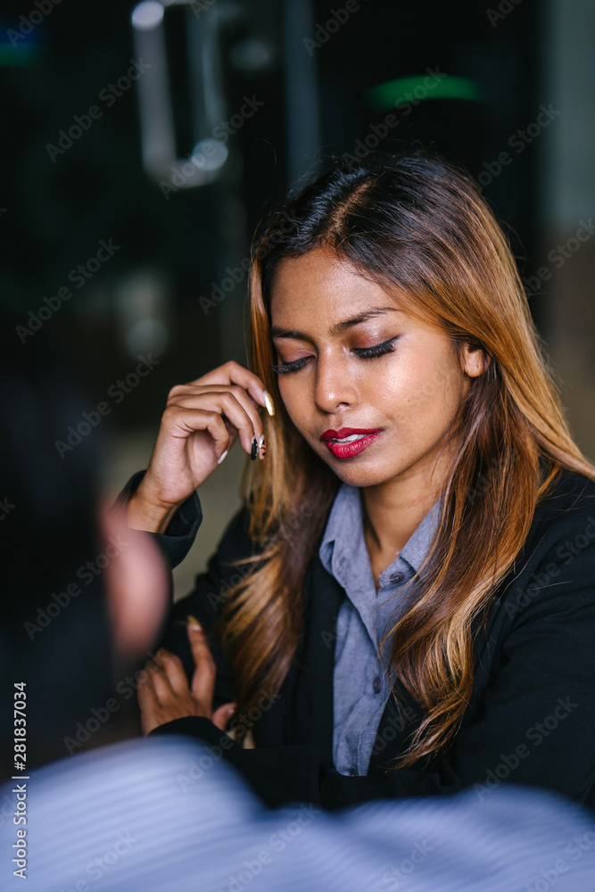 A portrait of a young, tanned, beautiful and confident Southeast Asian business woman. She is smiling confidently and happily. The woman is wearing a suit and sitting in an office in the city. A portrait of a young, tanned, beautiful and confident Southeast Asian business woman. She is smiling confidently and happily. The woman is wearing a suit and sitting in an office in the city.