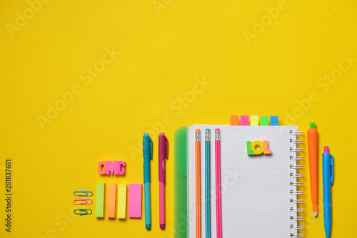 Colorful Back to School concept - open copy book with office and student supplies on yellow chalk. Space for text.