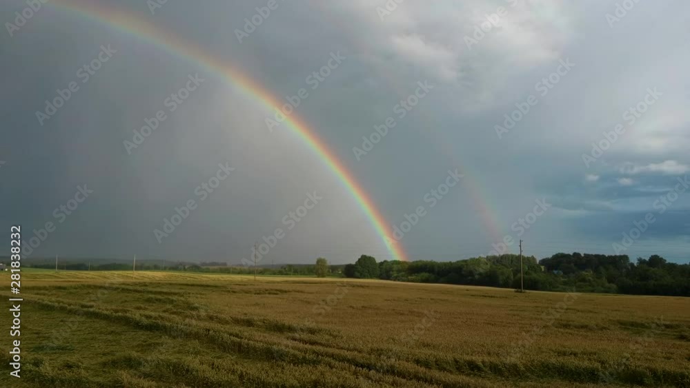Rainbow Above Wheat Field. Flight Sideward Ripe Crop Field After Rain and Colorfull Rainbow in Background Rural Countryside. Aerial Dron Shot. Rainbow Above Wheat Field. Flight Sideward Ripe Crop Field After Rain and Colorfull Rainbow in Background Rural Countryside. Aerial Dron Shot.