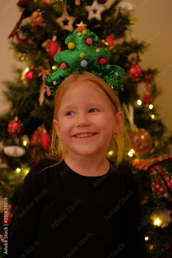 Little Girl With Christmas Tree Hair Ornament Posing In Front Of A Christmas Tree Little Girl With Christmas Tree Hair Ornament Posing In Front Of A Christmas Tree