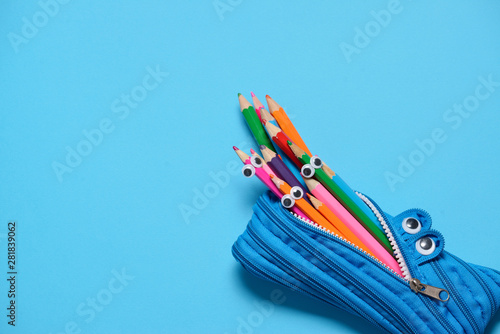 Fototapeta Funny Back to School concept - pencil case eating pencils on blue background
