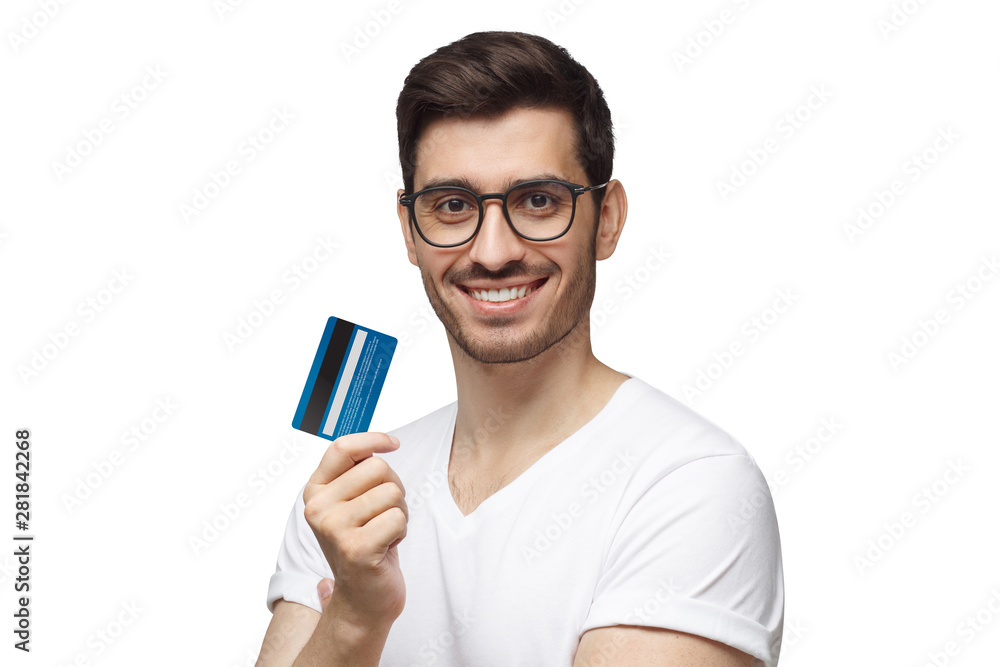 Happy smiling young man wearing eyeglasses, holding blue credit card, isolated on white background Happy smiling young man wearing eyeglasses, holding blue credit card, isolated on white background
