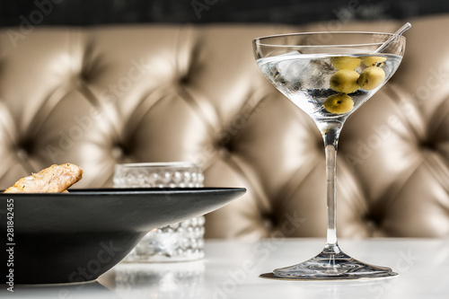 Beautiful glass of martini with olives accompanied by a gourmet dish.