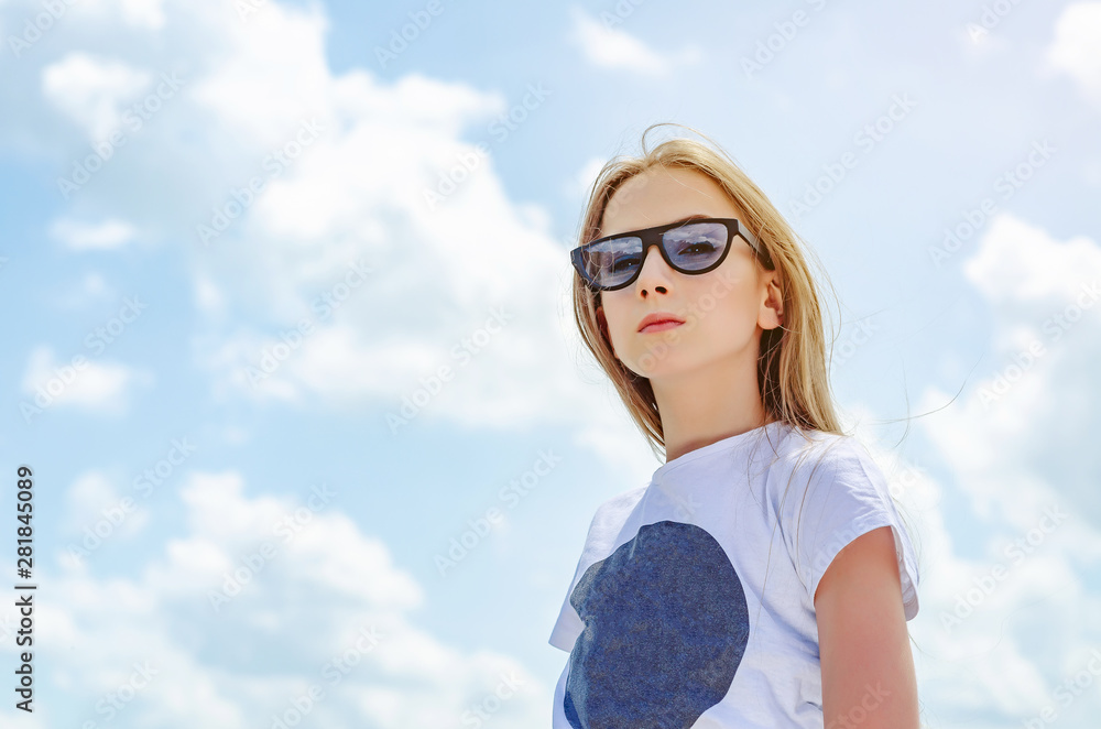Summer portrait of a blonde girl in sunglasses on a background of the sky with clouds Summer portrait of a blonde girl in sunglasses on a background of the sky with clouds