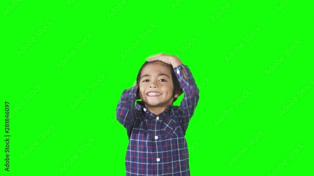 Attractive little boy posing in the studio while tidy up his hair. Shot in 4k resolution with green screen background Attractive little boy posing in the studio while tidy up his hair. Shot in 4k resolution with green screen background